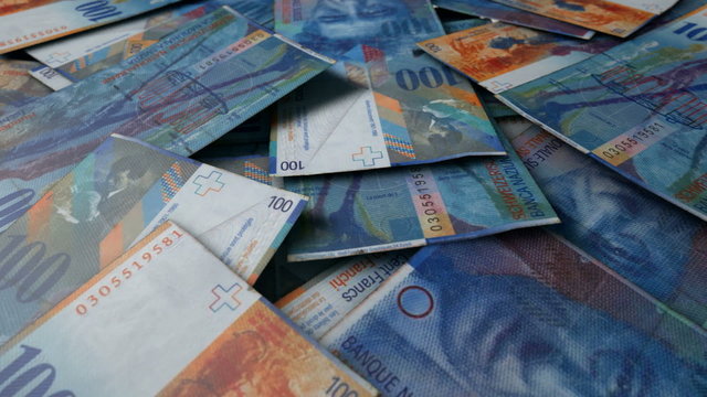 An extreme close up pan of a pile of randomly scattered swiss franc banknotes
