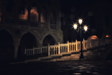 bridge via the Palace channel, a lamp and a wall of Doges Palace at night during a rain, Venice © Shchipkova Elena