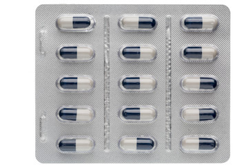 Closeup dark blue and white capsules in medication blister packs