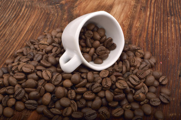 Roasted brown coffee beans & mug on wooden table