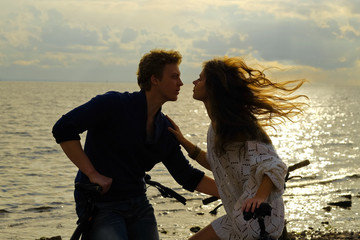 couple of lovers sitting on the bikes on the coast at sunset