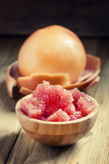 Juicy flesh pink grapefruit in the wooden bowl, selective focus