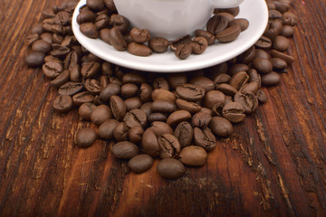 Roasted brown coffee beans & mug on wooden table