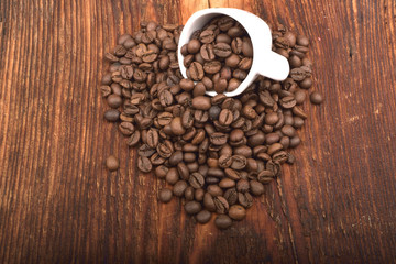Roasted brown coffee beans & mug on wooden table