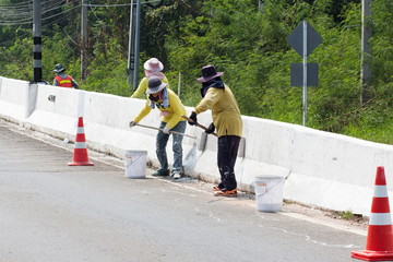 Workers paint white color on the road