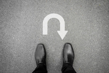 Black shoes standing in front of u turn symbol