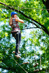 Naklejka na ściany i meble Adventure climbing high wire park - woman on course in mountain