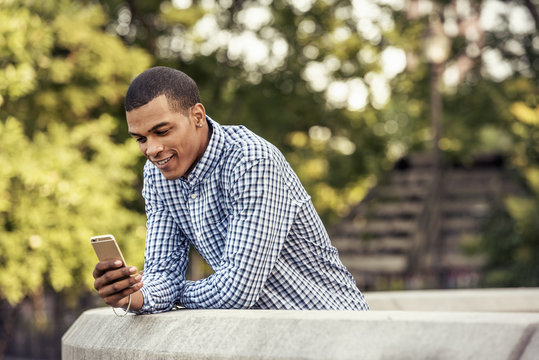 A man leaning on a parapet looking at a smart phone