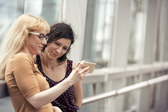 Two women side by side, looking at a cell phone. 
