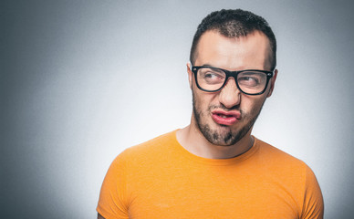 Nervous funny nerd guy against gray background. Angry man looking to side, copyspace