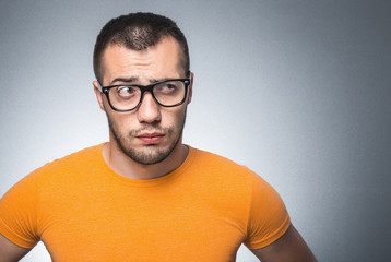 Careful young man. Guy thinking and looking to side, isolated on gray bacground with copy space for...