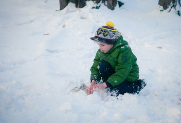 Fototapeta na wymiar Happy kid playing in the snow near a forest