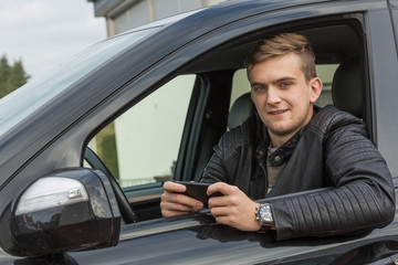 blonde young adult using smartphone and sitting inside of a car