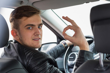 happy young blonde adult inside of a car. happy to have his new licence.