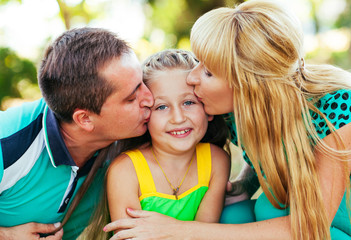 Fototapeta premium Young and beautiful family in the park. Mother, father and daugh