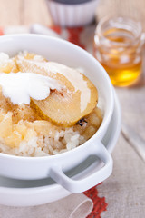 Rice with milk, cinnamon and pear with honey in a white bowl. Selective focus