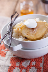 Rice with milk, cinnamon, honey, pear and yoghurt with  in a white bowl.