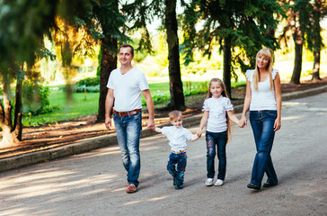 Happy young family walking down the road outside in green nature
