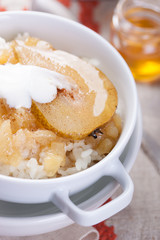 Rice with milk, cinnamon, honey, pear and yoghurt with  in a white bowl..