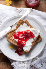 Toast with plum jam and cottage cheese on a white plate on an autumn background. Top view