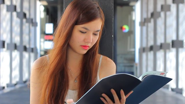 Portrait of thai adult beautiful girl Read and think in university.