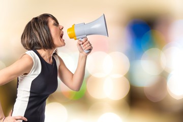 Pretty girl shouting with a megaphone over white background