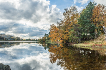 Autumn by the lake / Autumn colored trees reflecting in a quiet lake