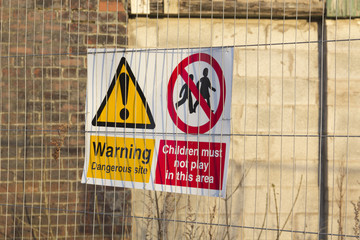 Dangerous building sign warning children not to play on the site of a derelict building.