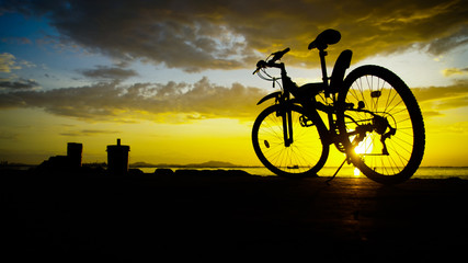 Silhouette of mountain bike with sunset sky at sea