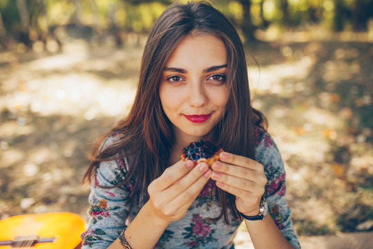 Closeup of beautiful teenage girl holding a tartatel with berries outdoors. Cute hipster brunette young woman on autumn day