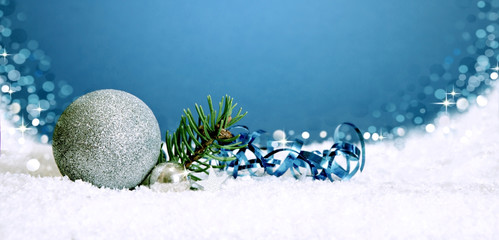 Christmas silver bauble and snow isolated on blue .