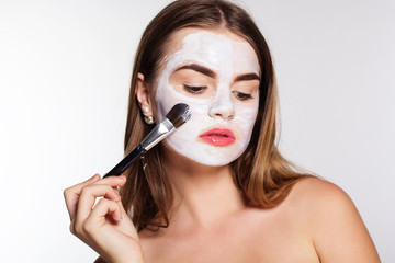 Beautiful girl applying clay facial mask