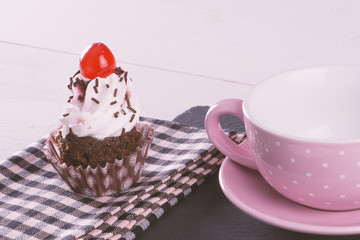 Cupcake over napkin point to a cup and a pink dish