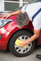 Handyman Cleaning Car Wheel With Sponge