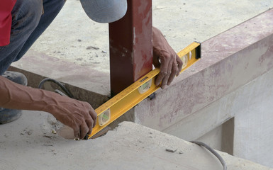 Spirit builder level/Cropped image of welder hands checking level on construction site.