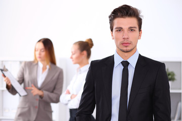 Cheerful business man in office with colleagues in the background, sturt  up team