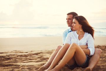 Fototapeta na wymiar Couple Relaxing on the Beach Watching the Sunset