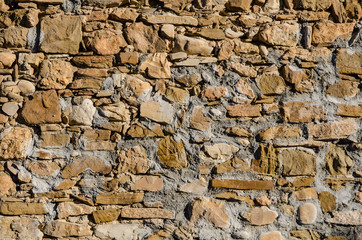 weathered stone wall of a very old building on a sunny day