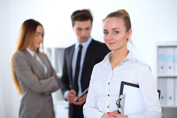 Obraz premium Pretty businesswoman in office with colleagues in the background