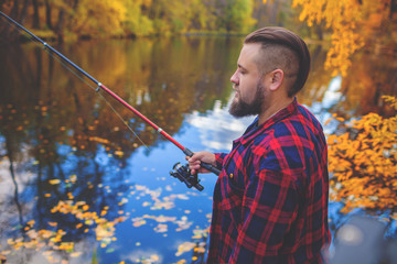 Young Man Fisherman bearded fishing with rod. River on background