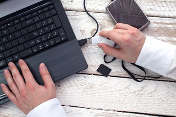Man's hand puts pendrive into laptop. Concept of data storage.