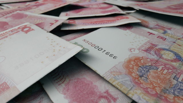 An extreme close up pan of a pile of randomly scattered chinese yuan banknotes