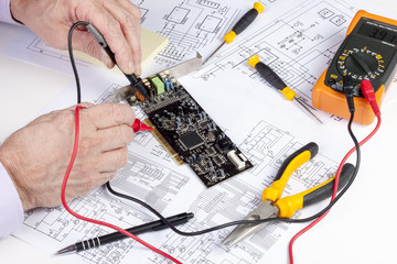 Electronics engineer testing a computer PCI card with a multi meter