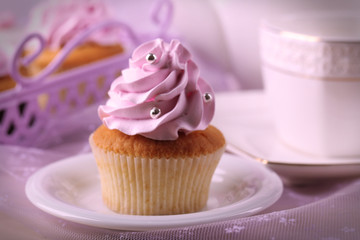 Tasty cupcake on saucer, on light background