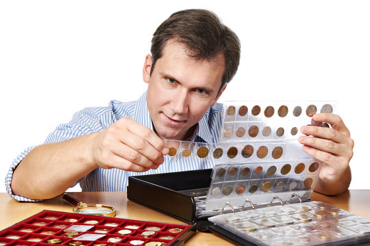 Man numismatist examines his collection of coin