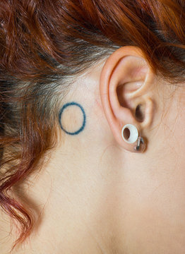 girl ear with piercings and tattoo