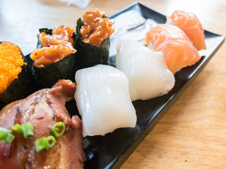 Squid sushi with variety of sushi on black dish