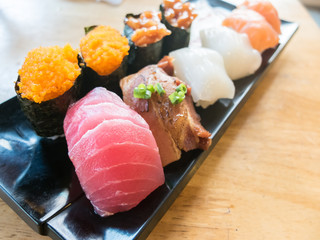 Tuna sushi with variety of sushi on black dish