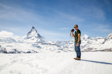Fototapeta na wymiar A man standing on the snow holding camera with the background of