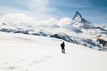 Fototapeta na wymiar A man standing on the snow looking at the background of Matterhorn.